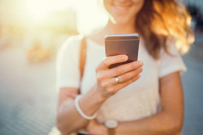 Symbol image of woman holding a mobile phone in her hand